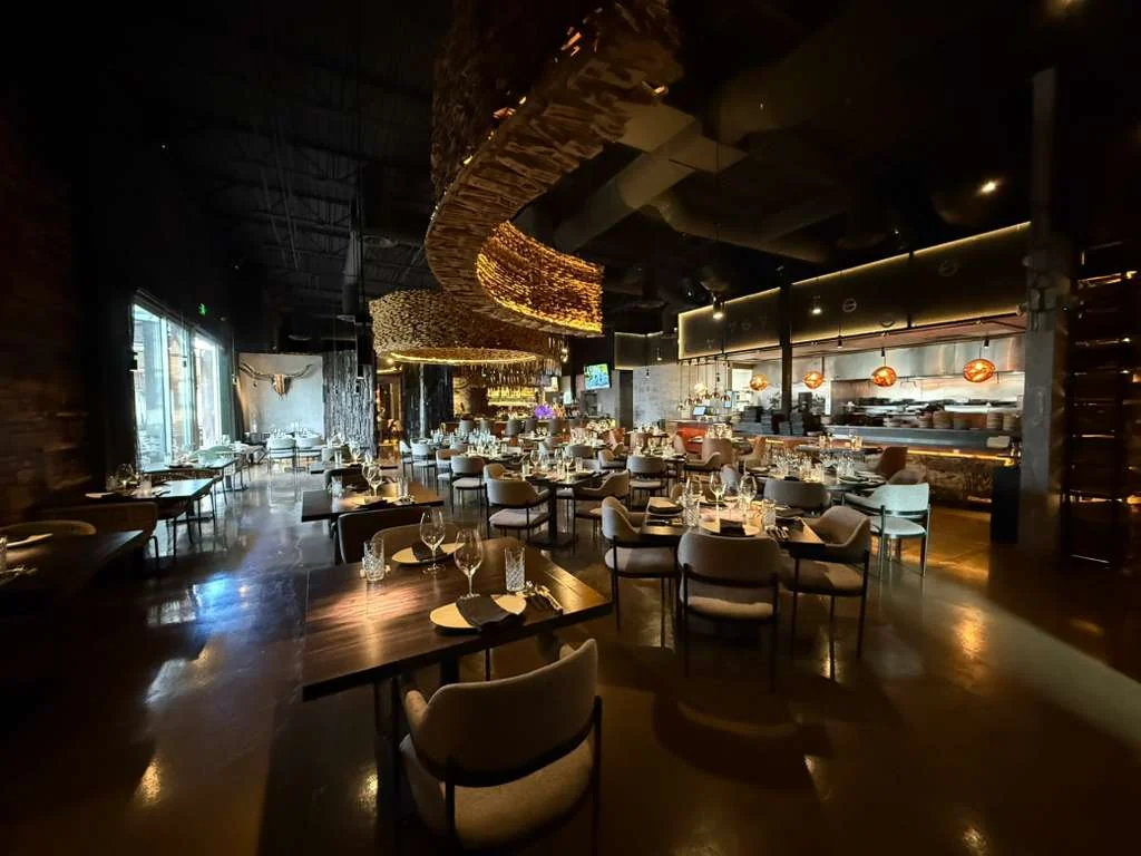 Origen’s dining room with dramatic timber chandeliers, warm lighting, and wood details